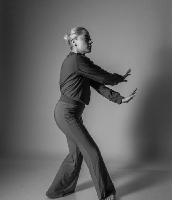 Woman performing a graceful, fluid cardio movement in a calm studio setting.